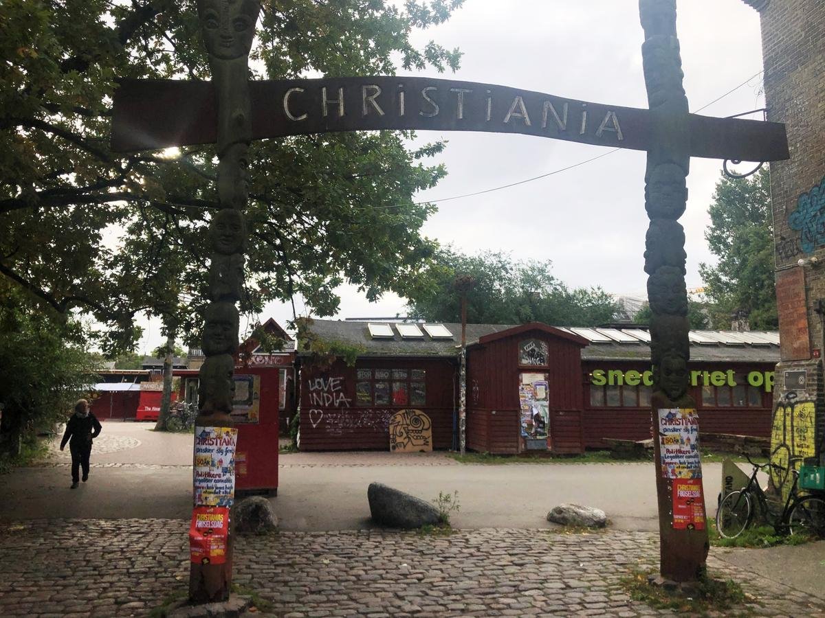 Eine Frau geht an einem Eingangsschild der Freistadt Christiania vorbei.