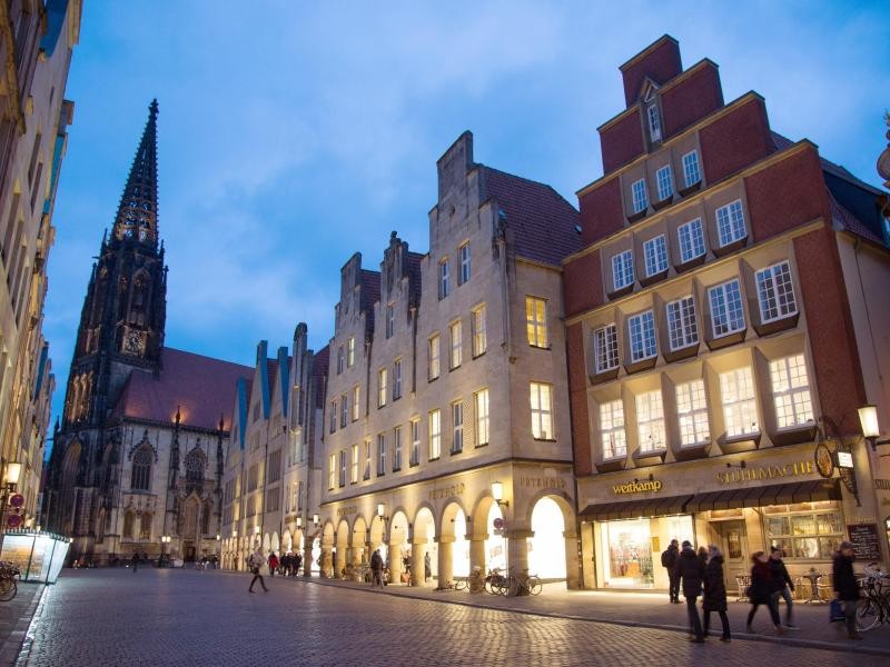 Einladend strahlen die Lichter der Geschäfte am Prinzipalmarkt in Münster - im Hintergrund erhebt sich die Lambertikirche.