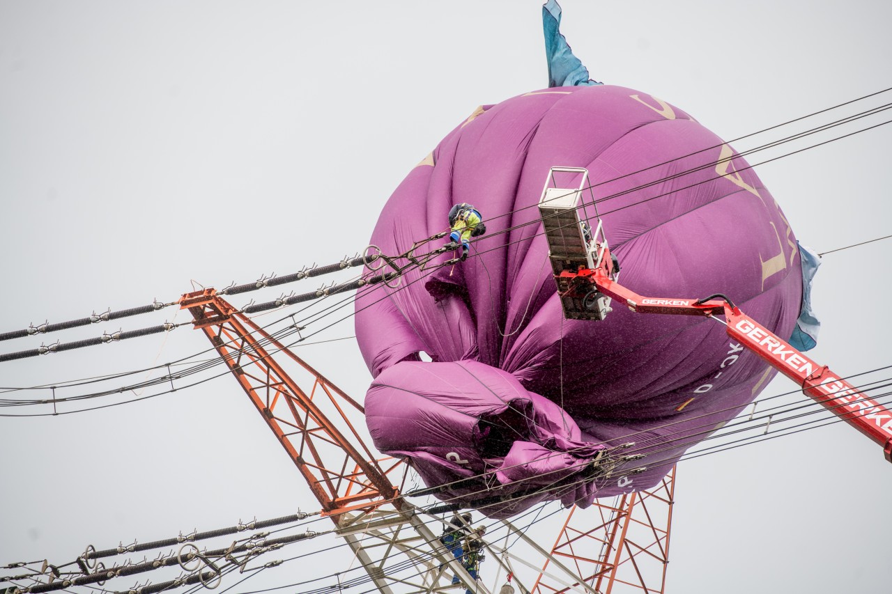 Experten versuchen, den havarierten Heißluftballon aus dem Strommasten zu bergen.