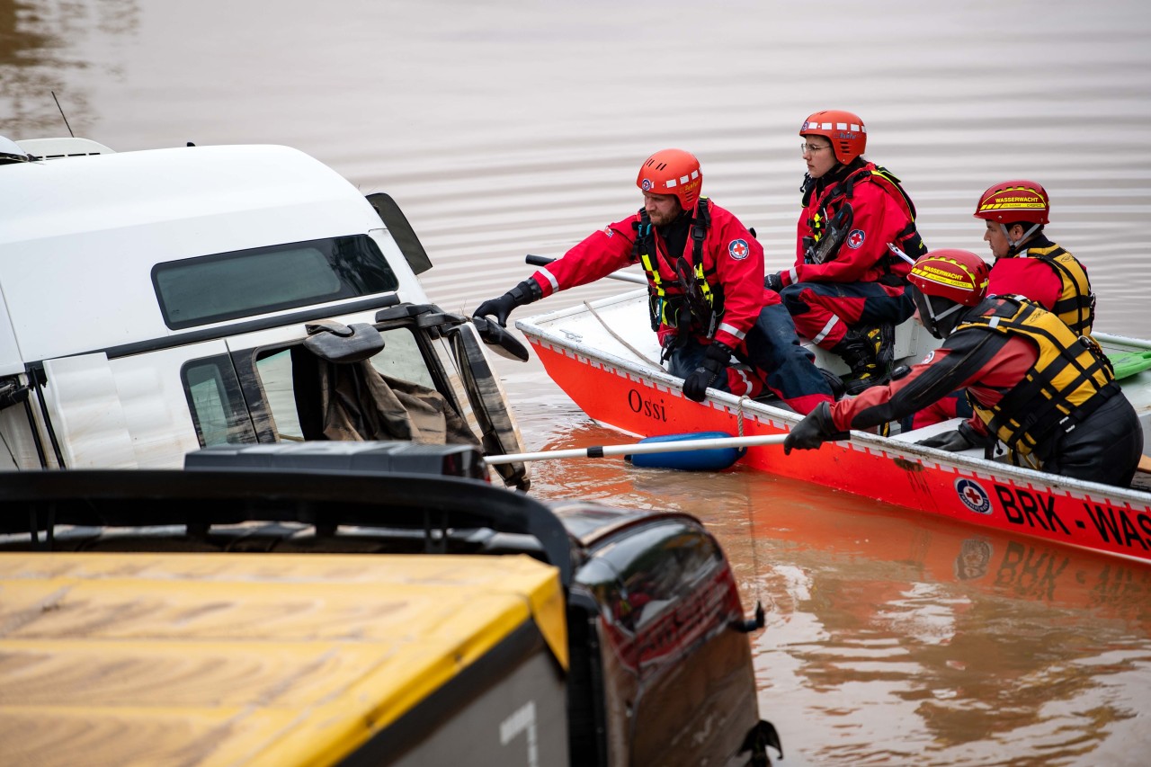 Hochwasser: Helfer der Wasserwacht untersuchen von einem Boot aus einen Lastwagen.