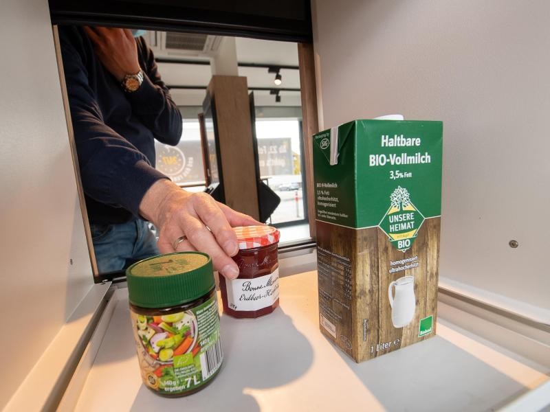 Ein Mann nimmt während eines Pressetermins zur Vorstellung eines voll automatisierten Edeka-Supermarktes ein Marmeladenglas aus dem Ausgabefach.