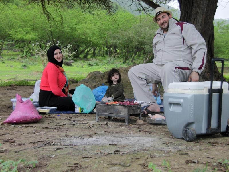 Vater Homam al-Jundi, seine Frau Hiba und Tochter Marwa ruhen unter einem Baum. Die Familie kommt aus Syrien und lebt seit dem Krieg in den Vereinigten Arabischen Emiraten.
