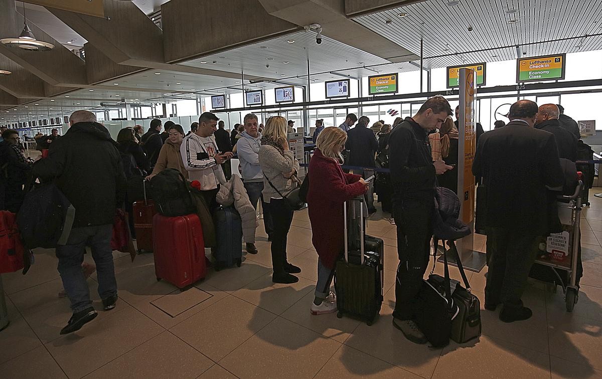 Reisende warten im Flughafen Köln/Bonn an einem Schalter. Der Flughafen wurde nach Schneefällen zwischenzeitig gesperrt.