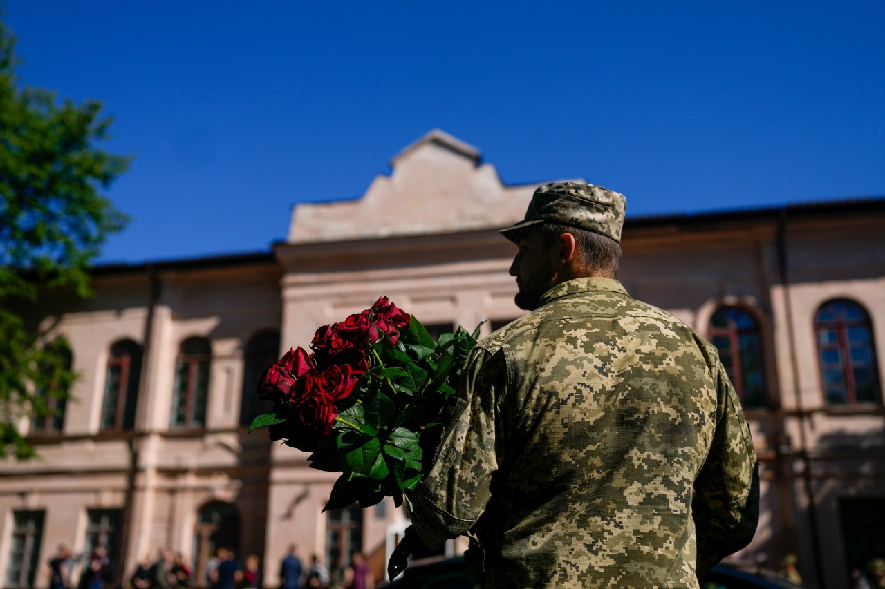 Ukraine: 100 Tage sind seit dem Angriff Russlands auf das Nachbarland vergangen. Hier hält ein ukrainischer Soldat Blumen während der Trauerfeier für seinen toten Oberst.