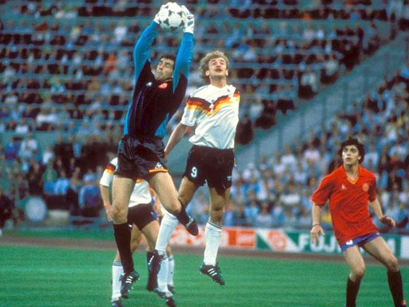 Die EM 1988 sollte Teamchef Beckenbauer nach der Vize-Weltmeisterschaft zwei Jahre zuvor den ersten Titel bescheren, aber nach einem glücklichen 1:1 gegen Italien in der Vorrunde und zwei 2:0-Siegen gegen Dänemark und Spanien war im Halbfinale gegen die Niederländer Endstation.In dieser Spielszene fängt Torwart Andoni Zubizarreta (Spanien) den Ball vor Rudi Völler.