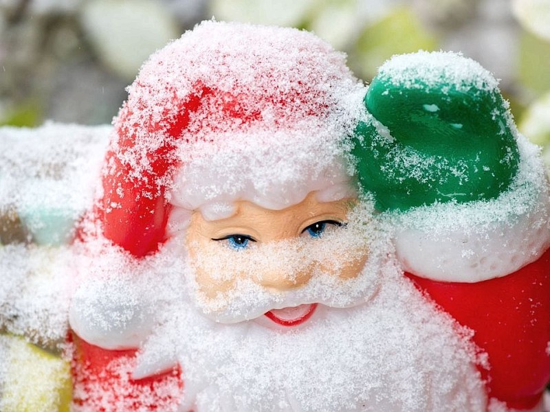Der schneebedeckte Weihnachtsmann grüßt freundlich.
