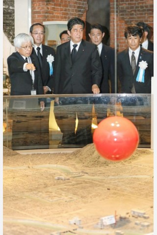 Viele Menschen gedenken  der Opfer des Atombombenabwurfs über Hiroshima vor 68 Jahren. Im Friedenspark steht noch immer eine Ruine als Mahnmal. Der Premierminister Japans, Shinzo Abe (Mitte), nimmt an den Gedenkfeierlichkeiten teil. Er unterhält sich mit Kenji Shiga (links), dem Direktor des Friedensmuseums Hiroshima.