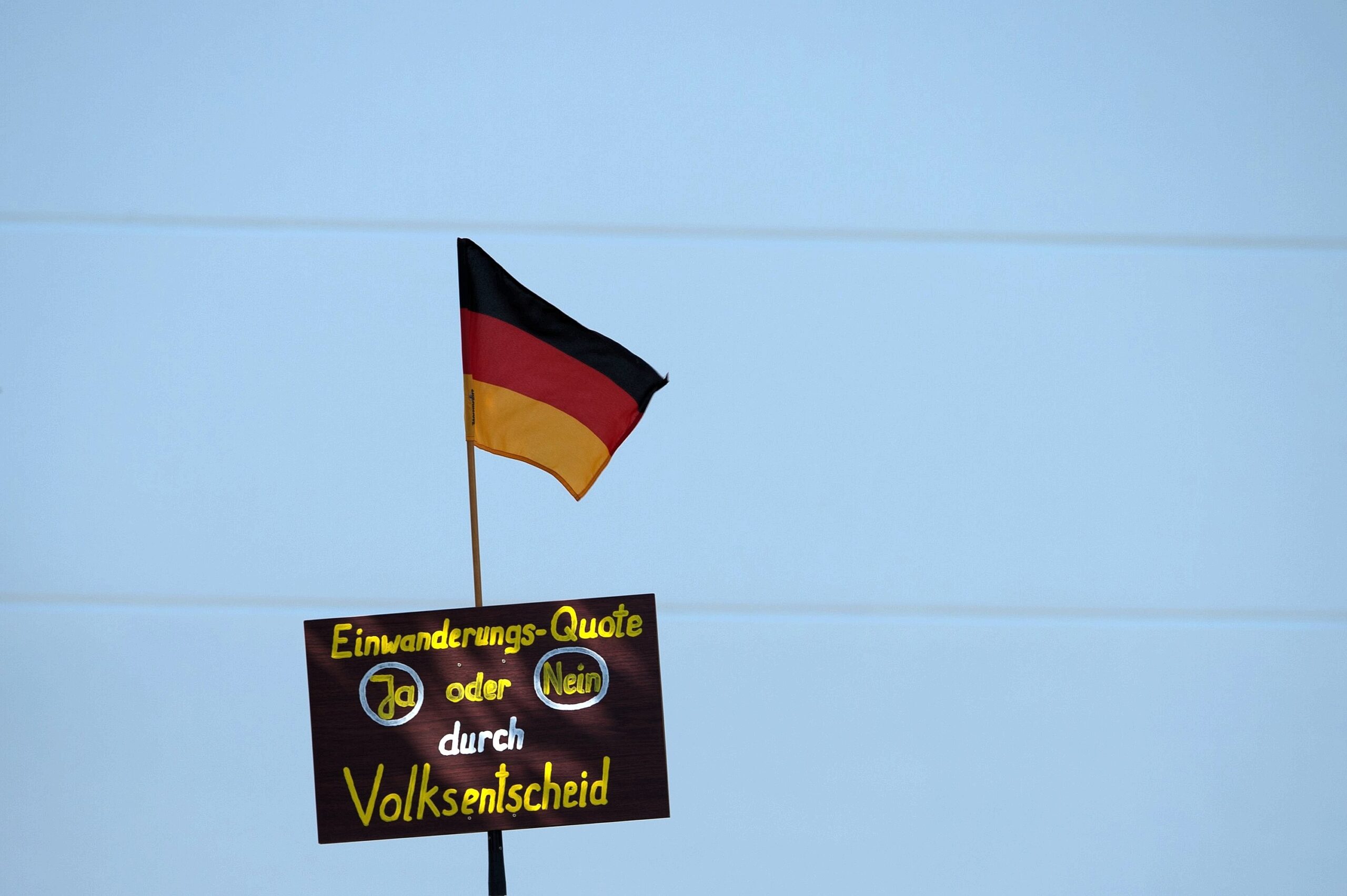 Demonstranten hielten während des Merkel-Besuches gegenüber der Flüchtlingsunterkunft Protestschilder und Deutschlandfahnen.