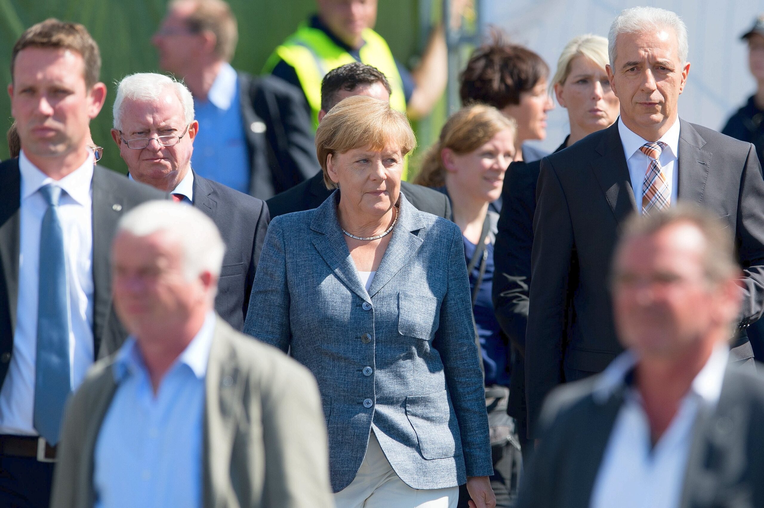 Bundeskanzlerin Angela Merkel und der Ministerpräsident von Sachsen Stanislaw Tillich (CDU, 2.v.r.) verlassen gut geschützt die Flüchtlingsunterkunft.