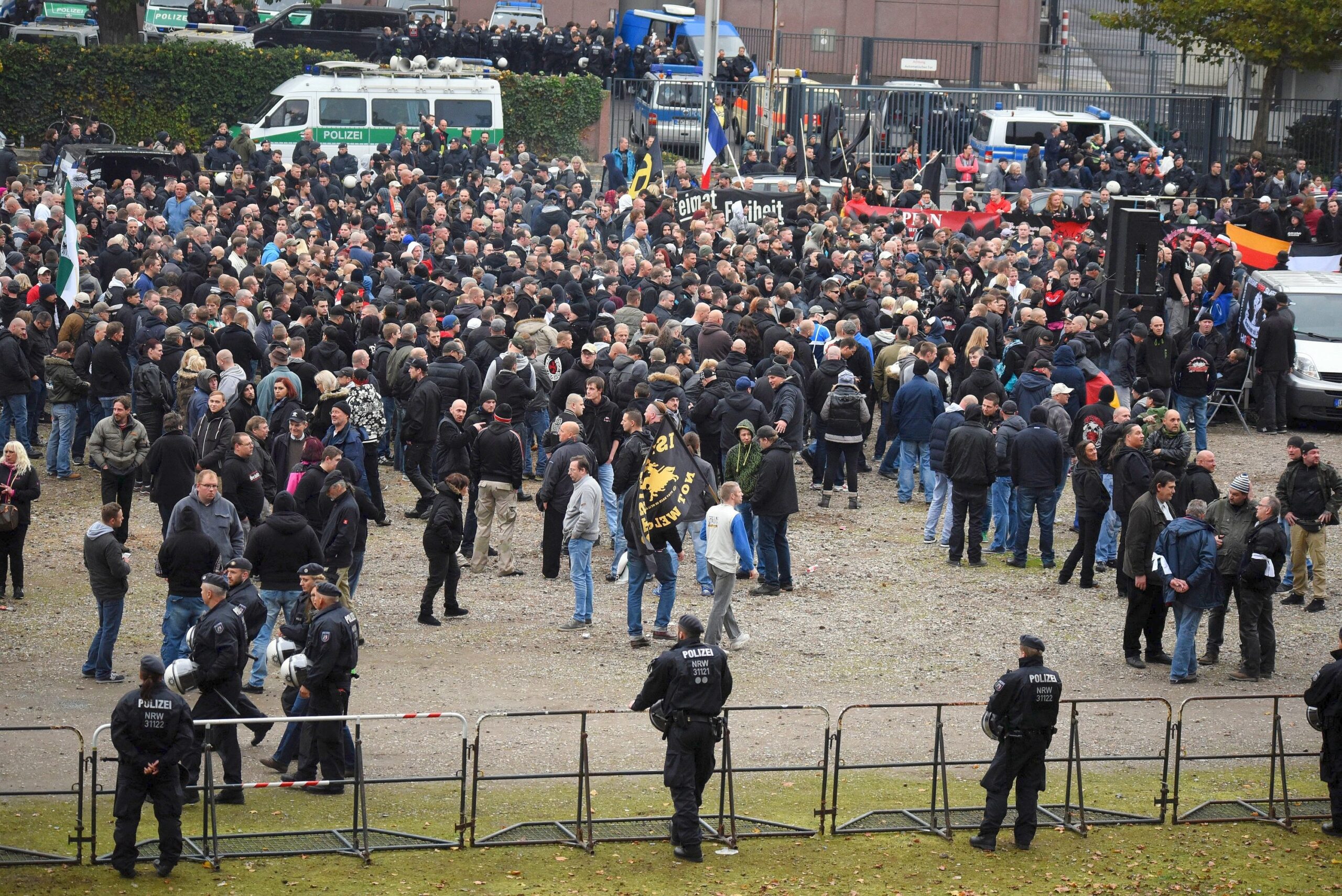Teilnehmer stehen am Sonntag in Köln bei einer Kundgebung der Gruppierung Hooligans gegen Salafisten (Hogesa), bewacht von Polizisten, auf dem Barmer Platz vor der  Messe...