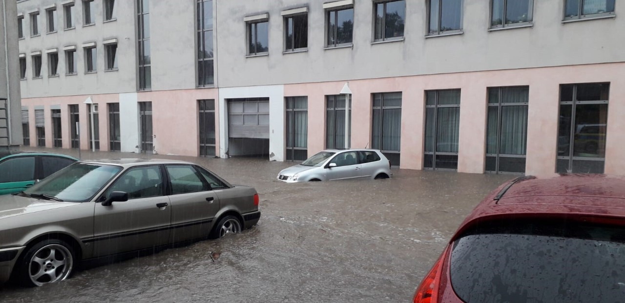 Nach dem Unwetter stehen Autos auf einem Parkplatz im Wasser.