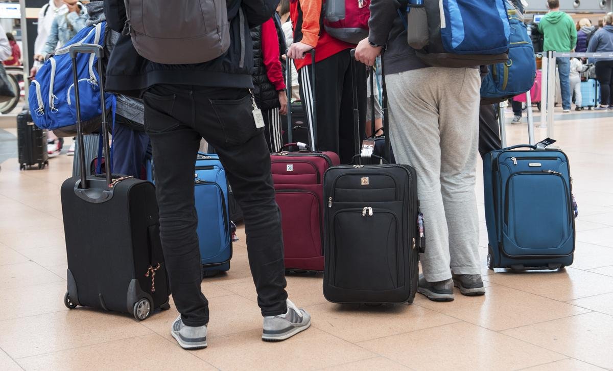 Reisende stehen mit ihrem Gepäck am Flughafen.