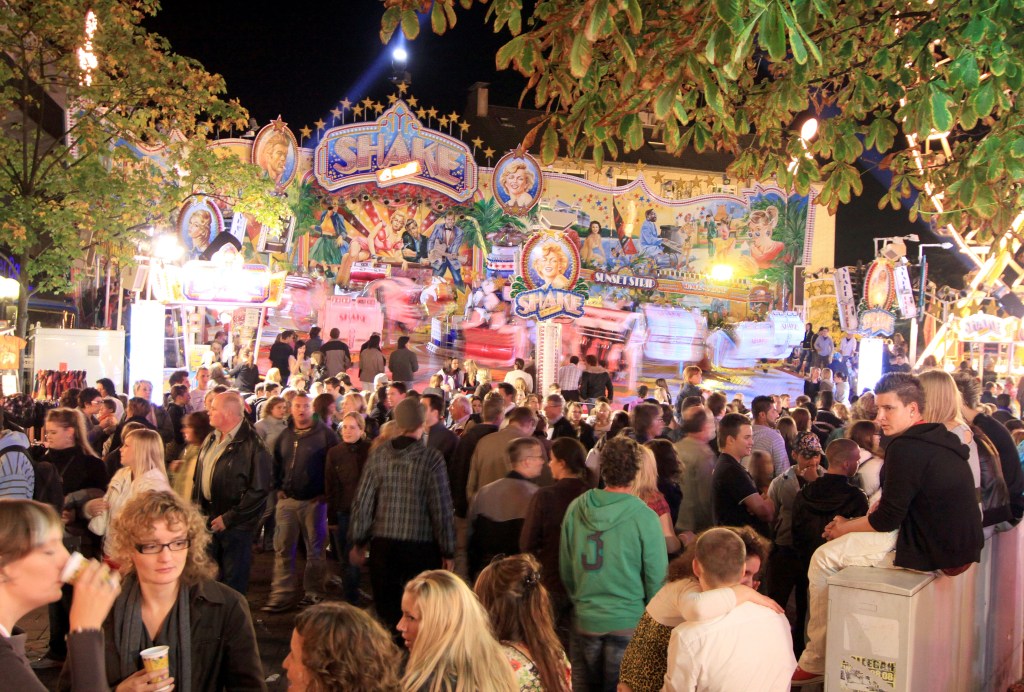 Auf der Haaner Kirmes in NRW tummeln sich Menschen vor einem Fahrgeschäft.