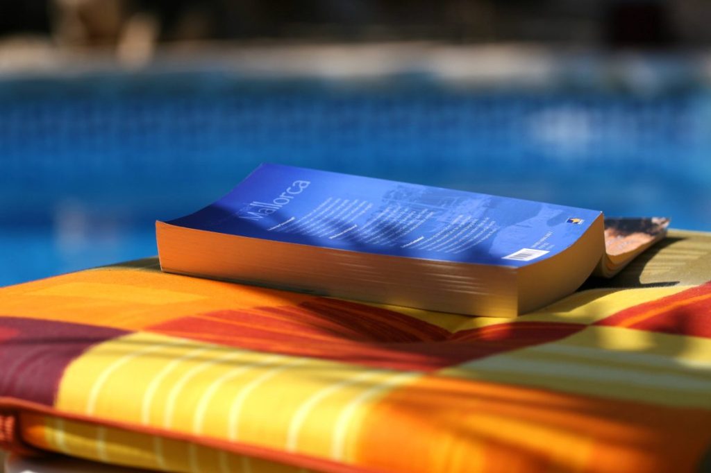 Ein Buch liegt auf einer Liege am Pool von Mallorca.