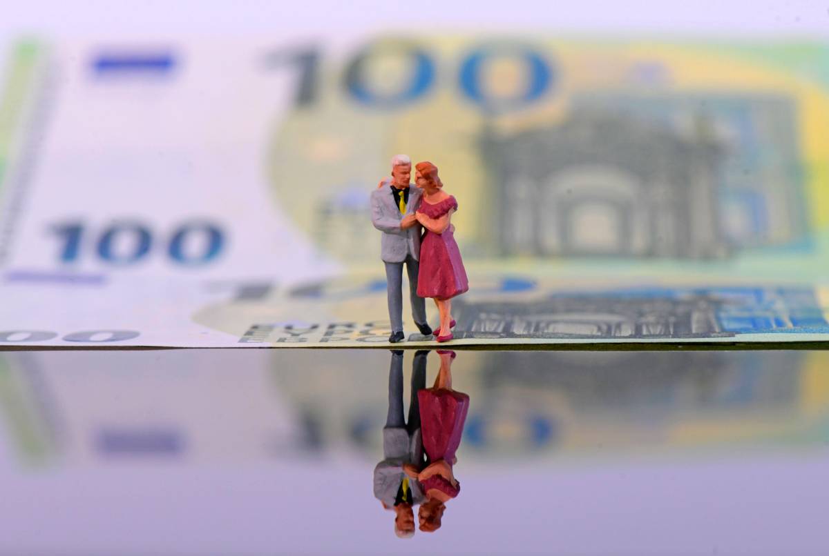 Ein Ehepaar umarmt sich vor der Kulisse eines 100-Euro-Scheins.