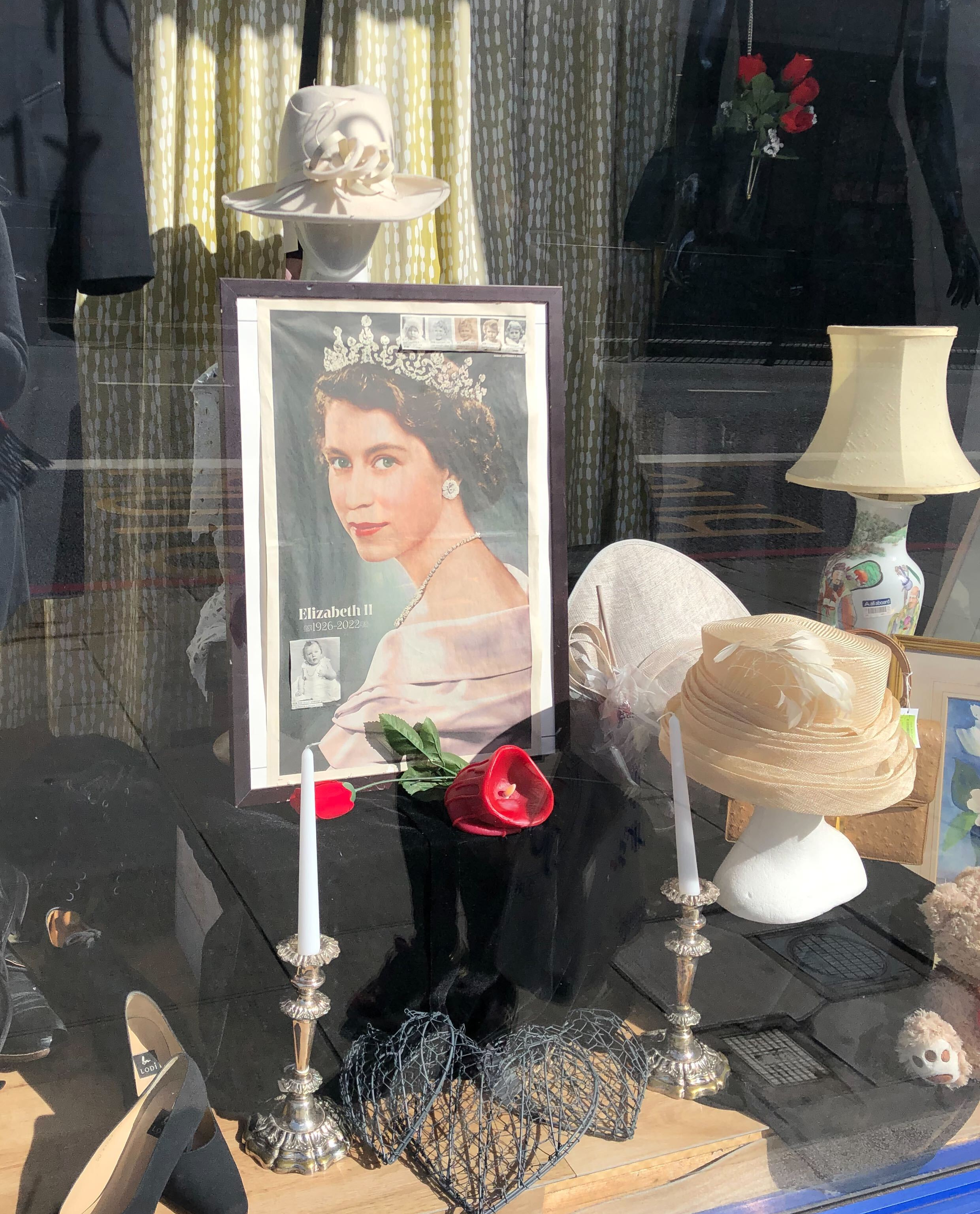 In einem Second-Hand-Shop ist das Porträt von Queen Elizabeth II. neben Kerzen, schwarzem Stoff und einer roten Rose aufgestellt worden.