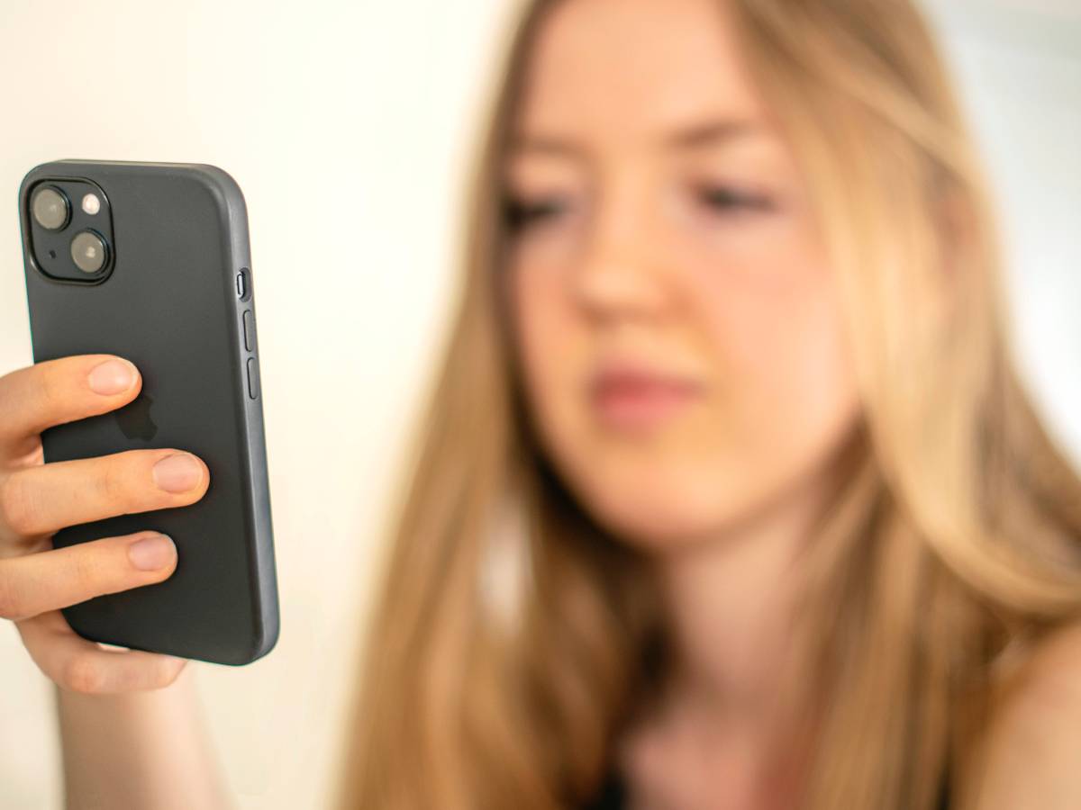 Eine junge Frau schaut auf ihr Handy.