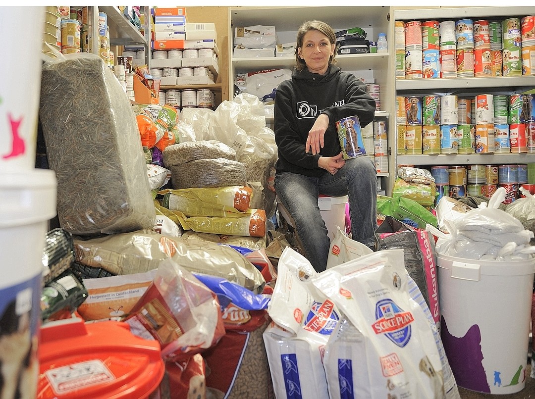 Nicole Meichele, Leiterin der Tiertafel, sitzt auf den gespendeten Futterbergen.
