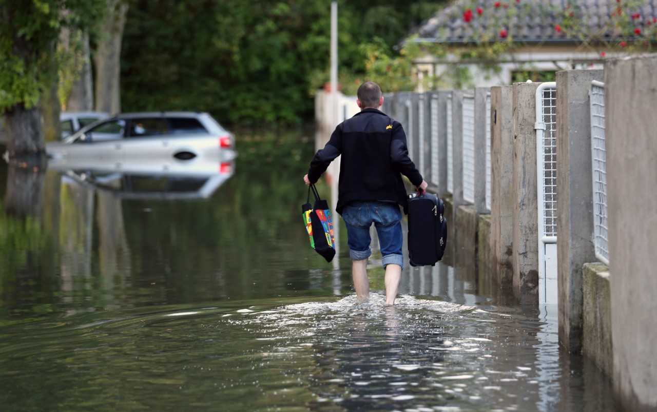 Ein Anwohner geht in Hamm über die überschwemmte Straße zu seinem Haus. Foto: dpa