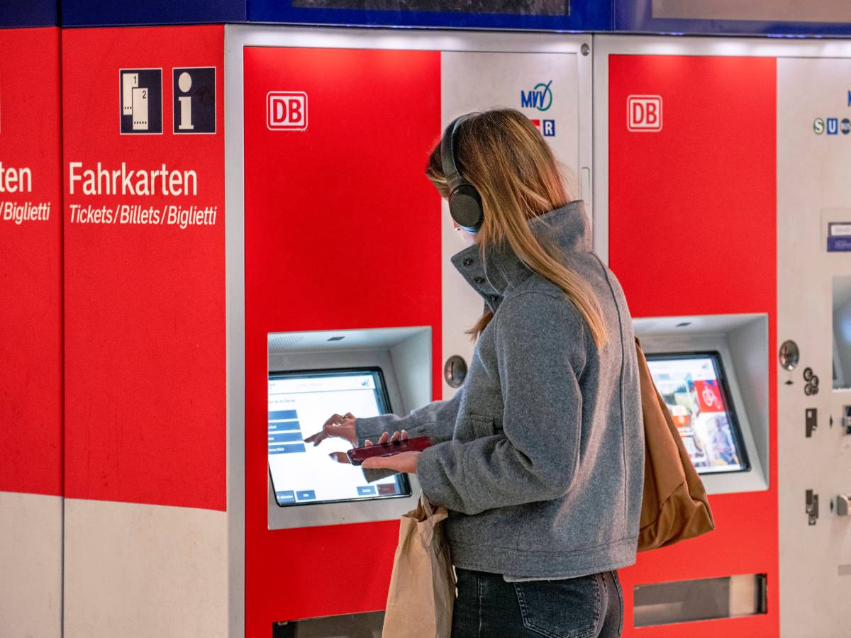 49-Euro-Ticket: Frau zieht ein Ticket am Fahrscheinautomaten der Deutshcen Bahn.