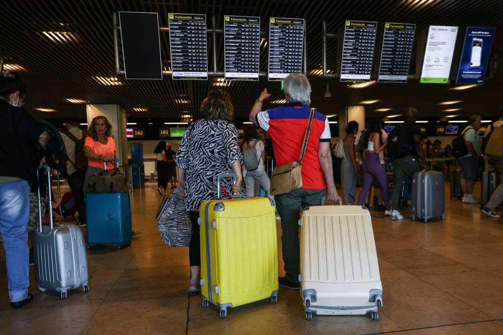 Passagiere gucken auf eine Infotafel am Flughafen in Madrid.