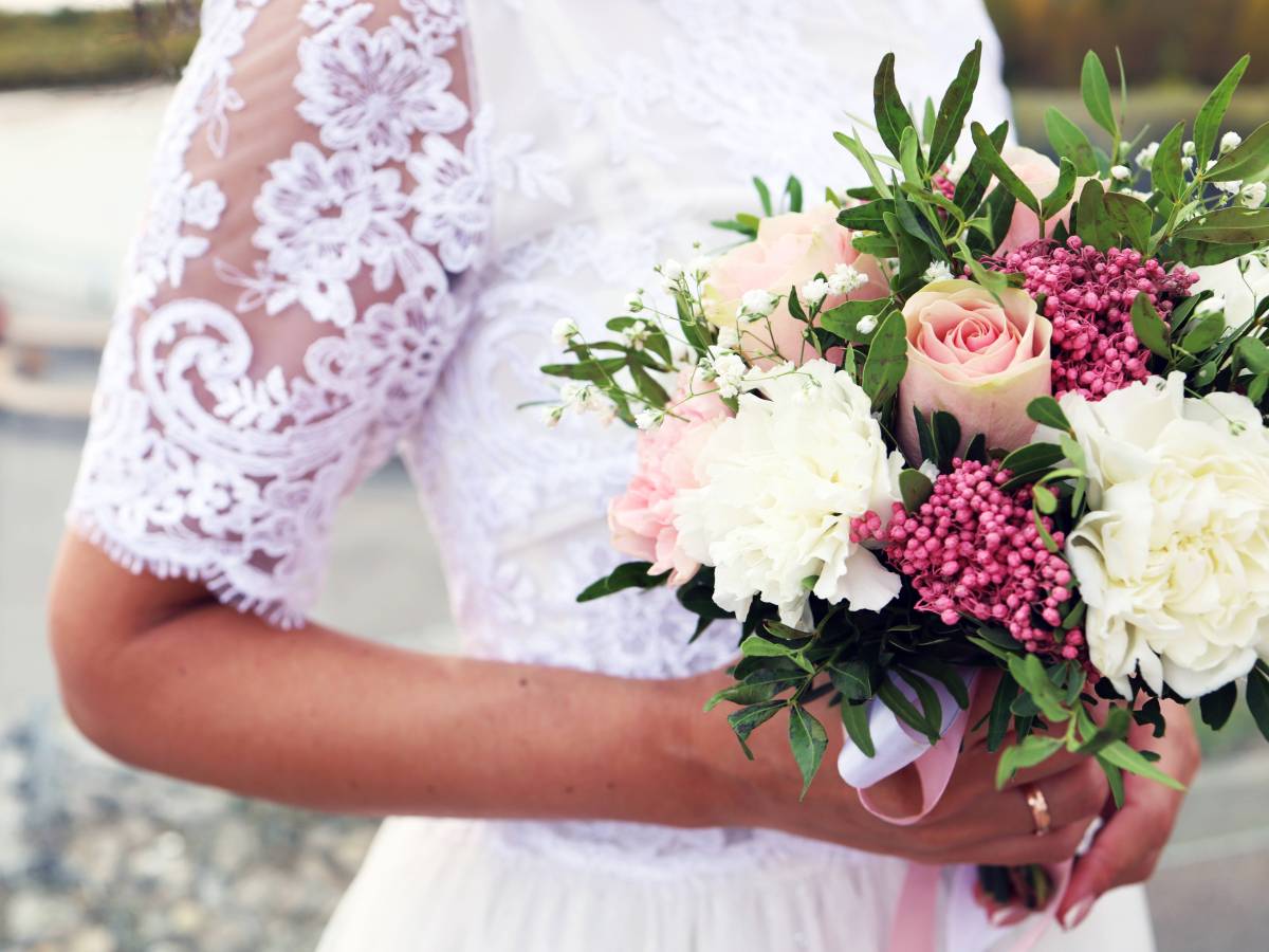 Hochzeit: Eine Braut trägt einen Strauß Blumen