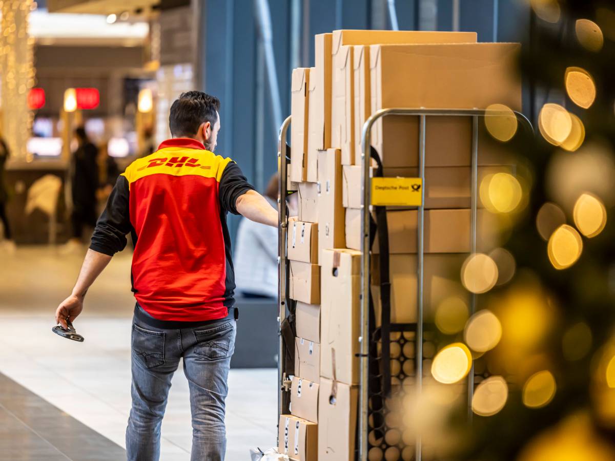 DHL: Ein Mitarbeiter liefert einen Haufen Pakete