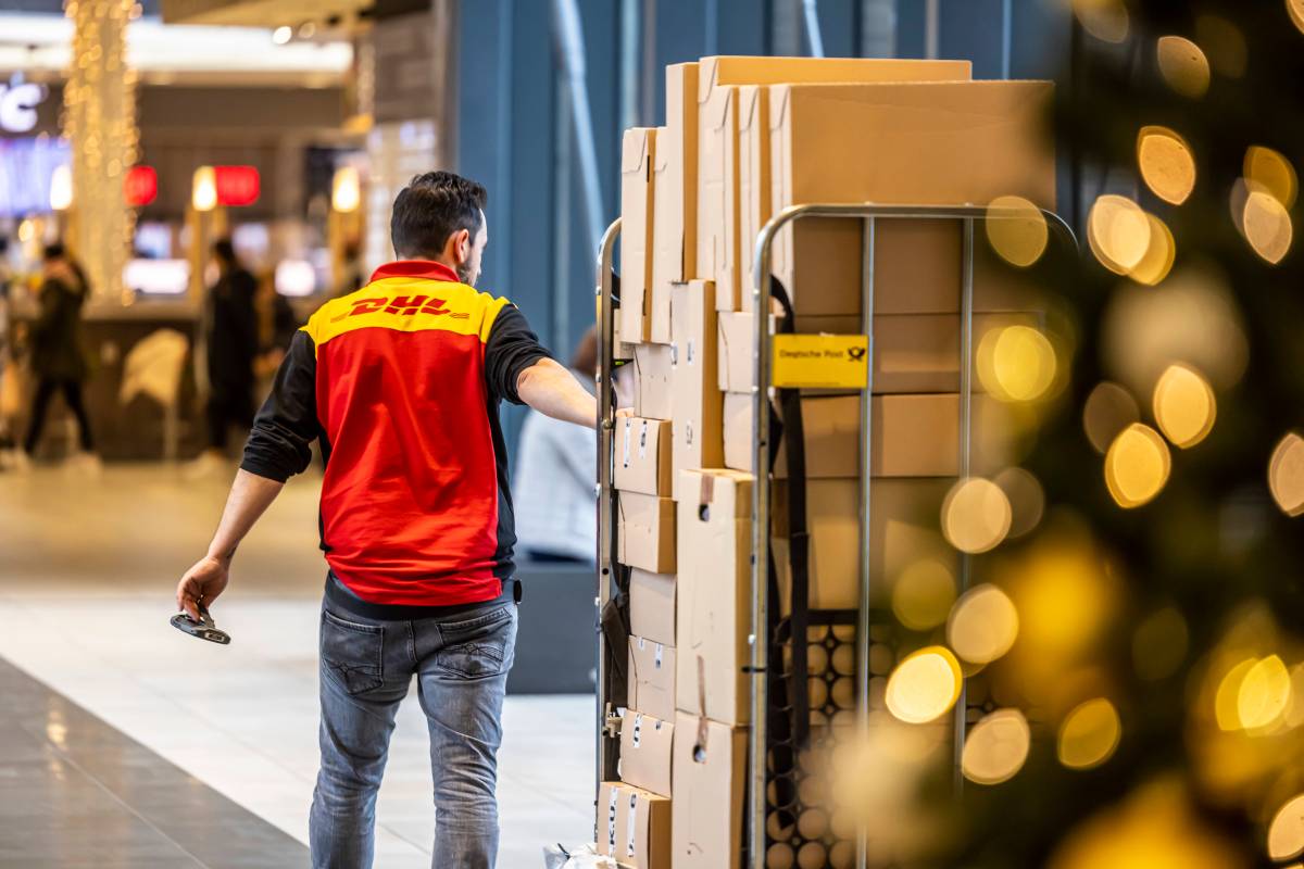 DHL: Ein Mitarbeiter liefert einen Haufen Pakete