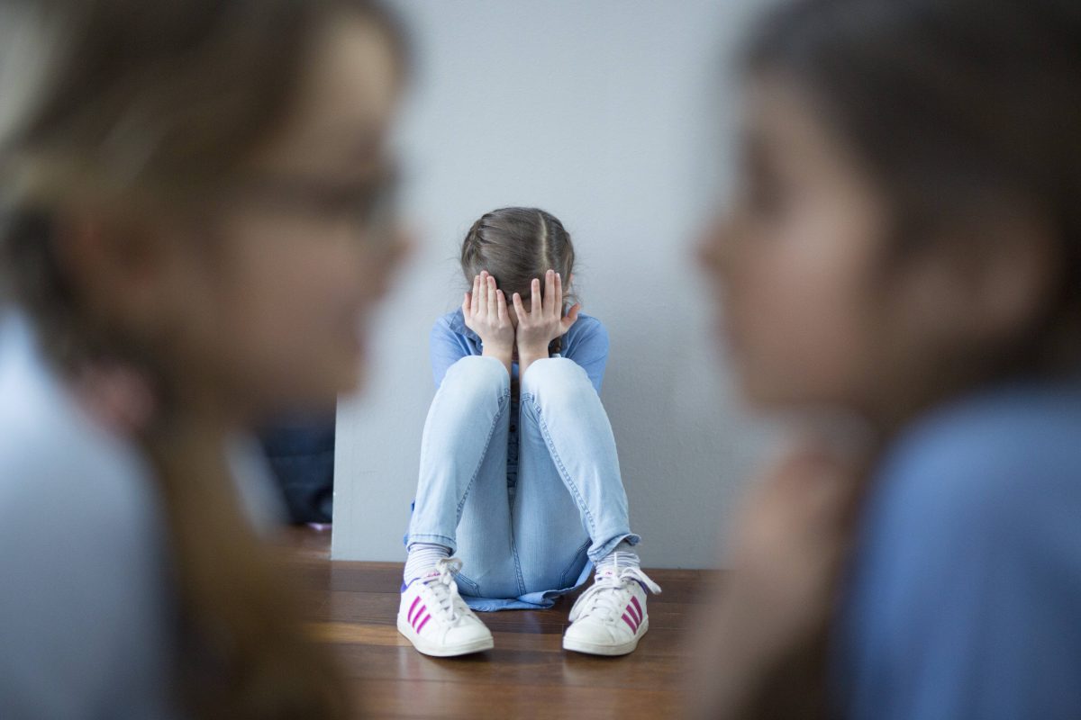 MÃ¤dchen mit Kopf in den HÃ¤nden auf dem Boden sitzend