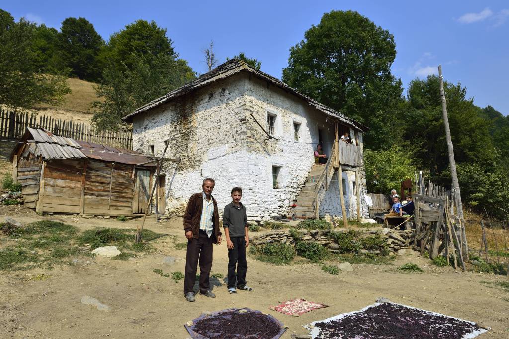 Albanische Familie steht vor ihrem alten Bauernhaus in Cerem, Nationalpark Valbonatal, albanische Alpen, Albanien.