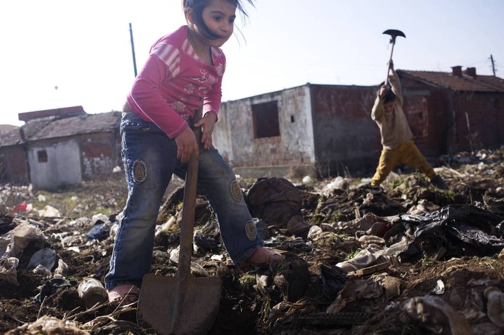 Kinder graben mit Schaufeln in einer wilden Müllkippe im Kosovo.