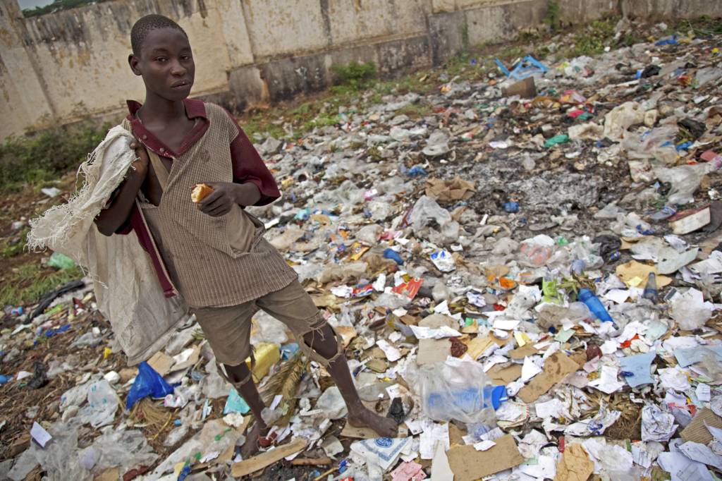 Ein Junge steht in einer Müllkippe und sucht nach Essbarem.