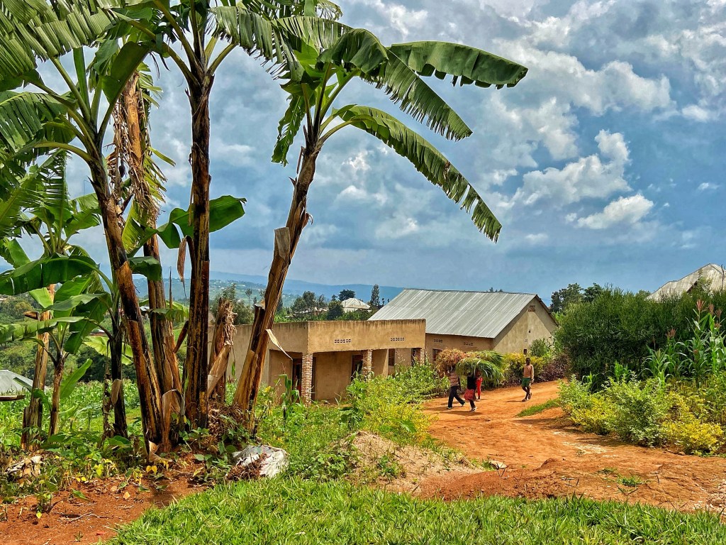 Menschen halten sich vor einer Haussiedlung in der Natur von Ruanda auf