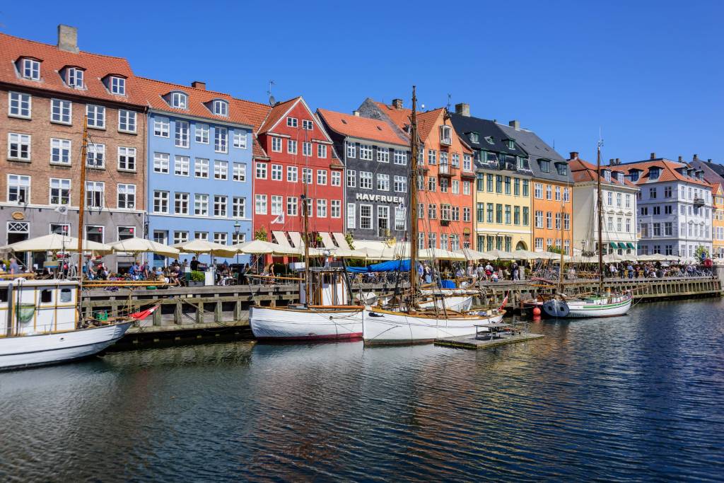 Zwei Boote stehen im Hafen von Kopenhagen (Dänemark) vor einer bunten Häuserreihe.