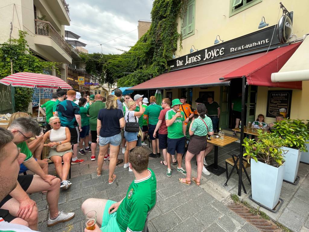 Zahlreiche in grünen Shirts gekleidete Menschen stehen vor einem Pub in Dublin (Irland).