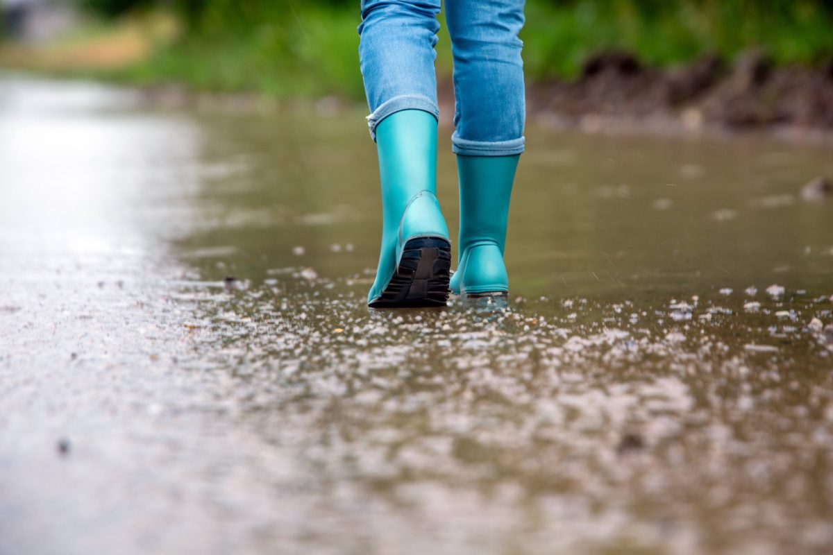 Frau läuft mit Gummistiefeln durch Regen
