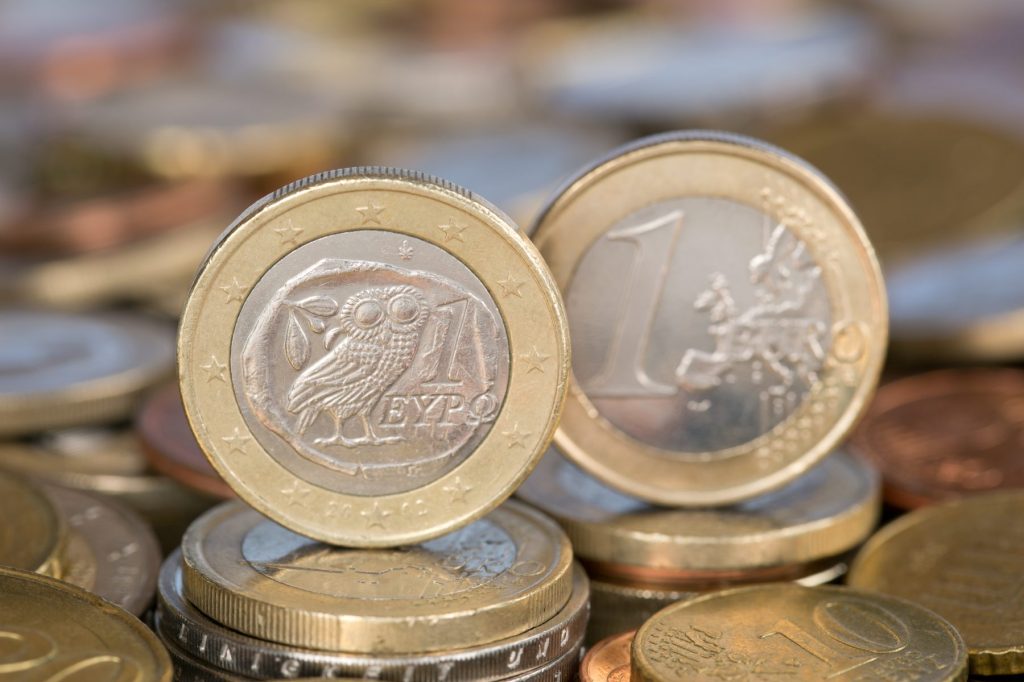 Zwei 1-Euro-Münzen aus Griechenland stehen auf ihrem Rand auf Geldstücken.
