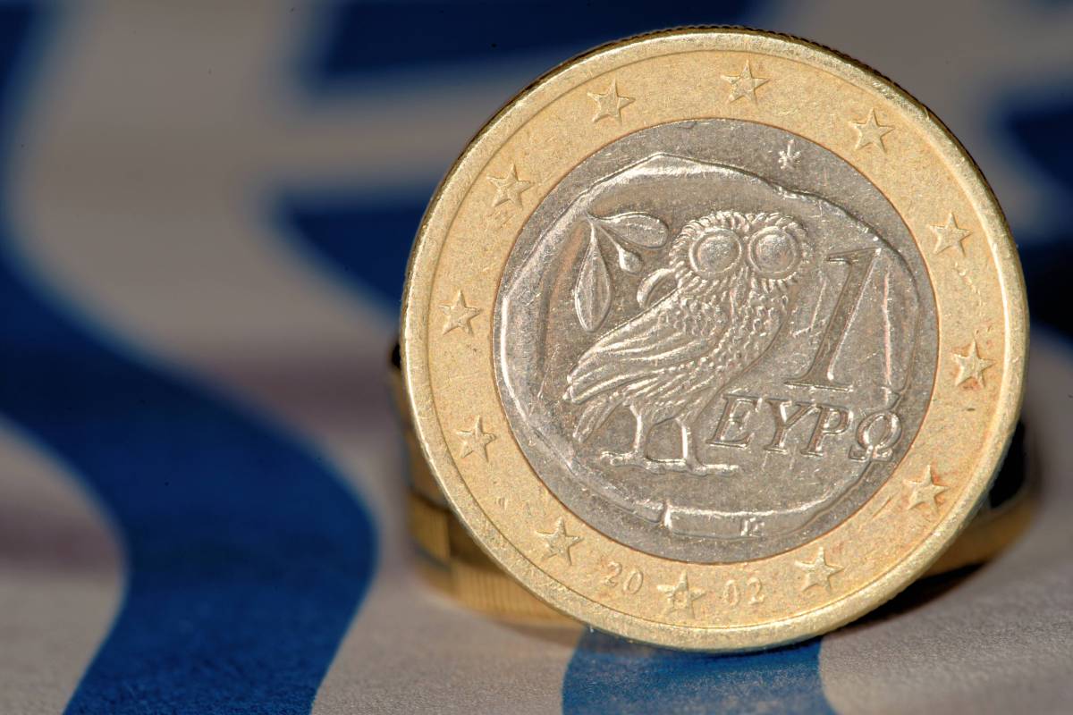 Eine 1-Euro-Münze aus Griechenland steht auf ihrem Rand, sodass die Rückseite mit der Eule zu sehen ist.