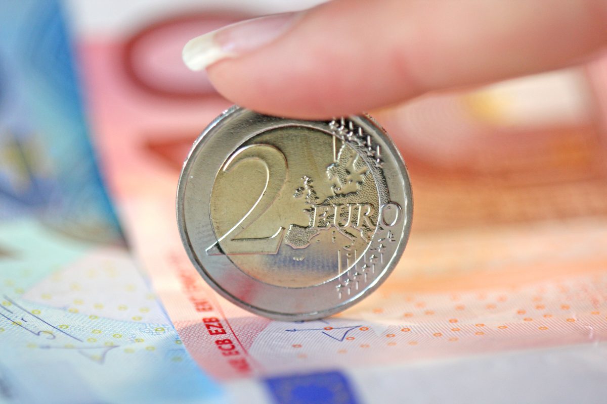 Eine 2-Euro-Münze ist von vorn zu sehen und steht auf einem 10-Euro-Schein.