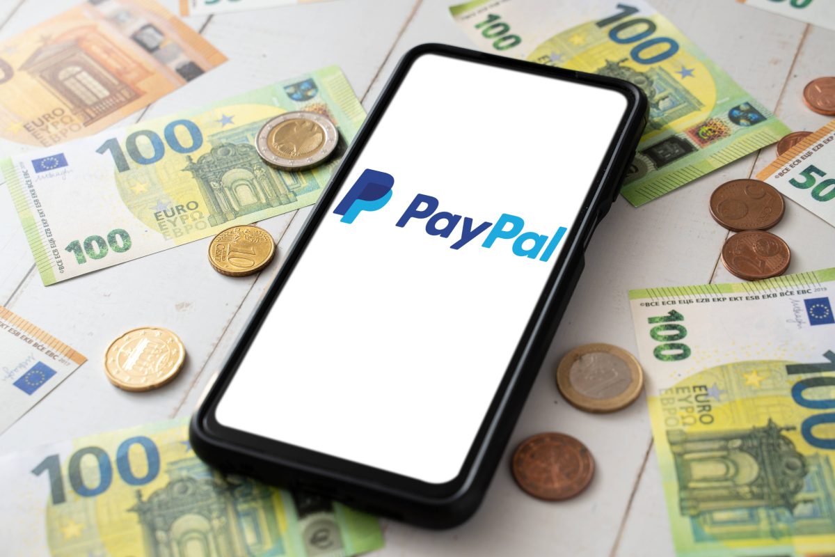 Paypal-App auf Handy. Geldscheine und Münzen