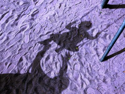 Erwachsener schauckelt Kind im Dunkeln, Schatten auf Sand