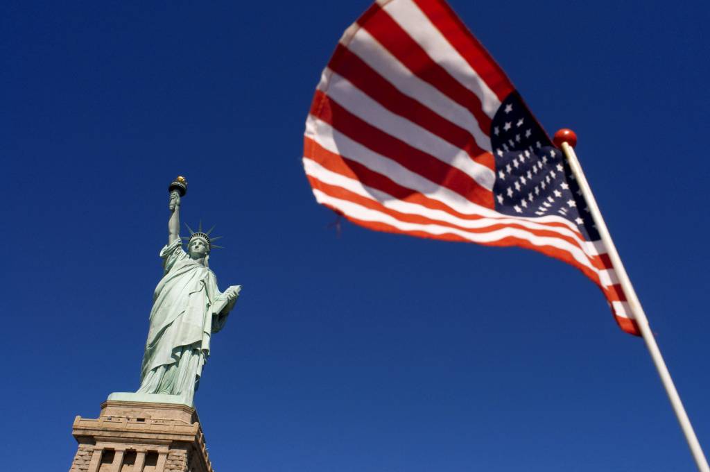 Die amerikanische Flagge weht vor der Freiheitsstatue in New York in den USA.
