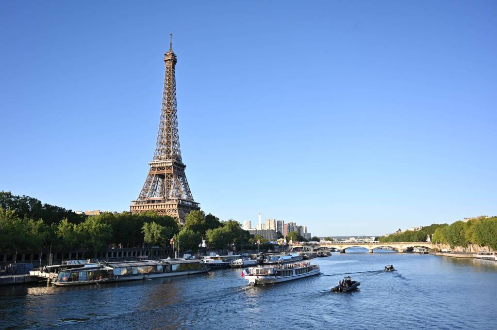 Ein Blick auf den Fluss, die Seine, der durch Paris fließt. Auf Wasser liegen Boote. Im Hintergrund der Eiffelturm