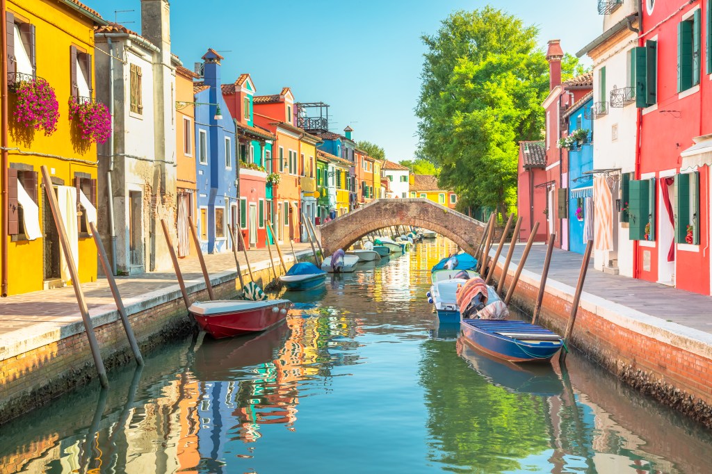 Kanal der Insel Burano fließt zwischen bunten Häuser und Booten in der Lagune von Venedig, Norditalien.