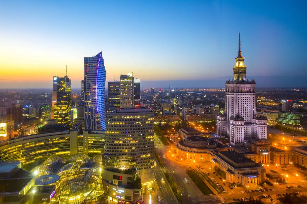 Ein Blick über das beleuchtete Zentrum von Warschau mit Kulturpalast bei Nacht.
