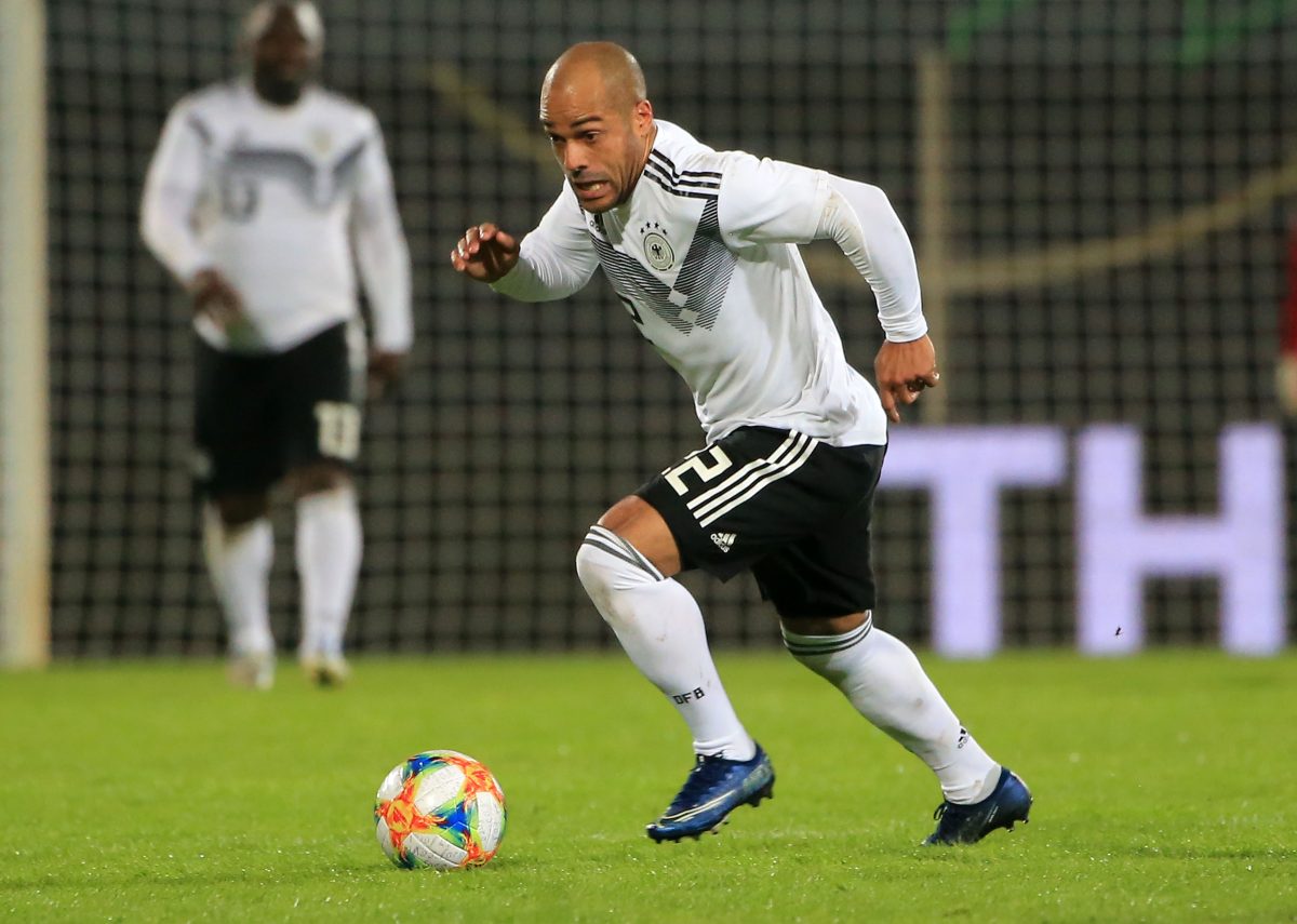 Auf dem Bild ist David Odonkor zu sehen. Er ist auf einem Fußballplatz. Er rennt einem Ball hinterher und trägt ein weißes Deutschland Trikot mit schwarzer Hose.