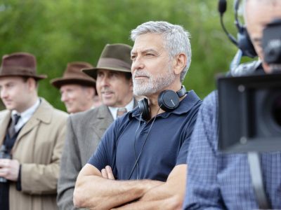 Schauspieler George Clooney. Er trägt schwarze Kopfhörer um den Hals und hat ein blaues Polo-T-Shirt an.