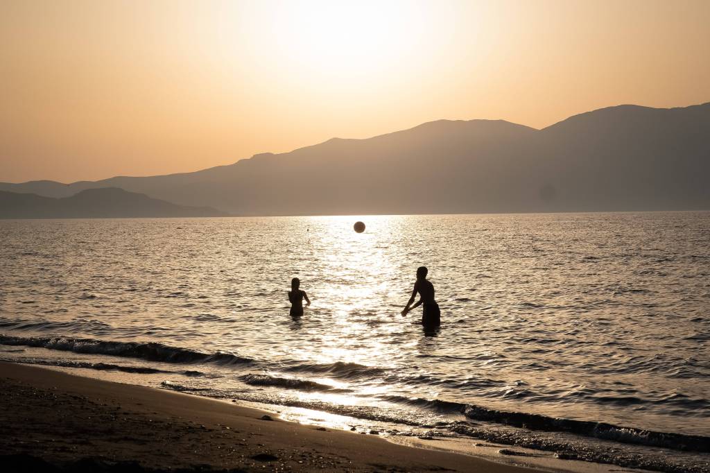 Zwei Menschen spielen Volleyball im Meer.