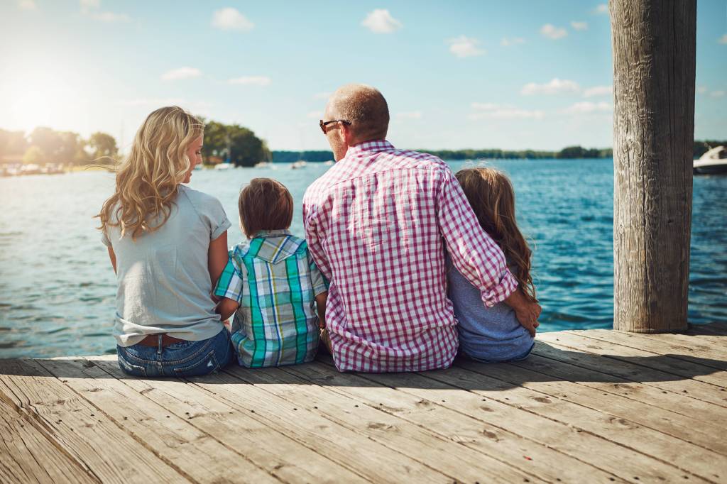 Familie sitzt auf einem Steg am See.
