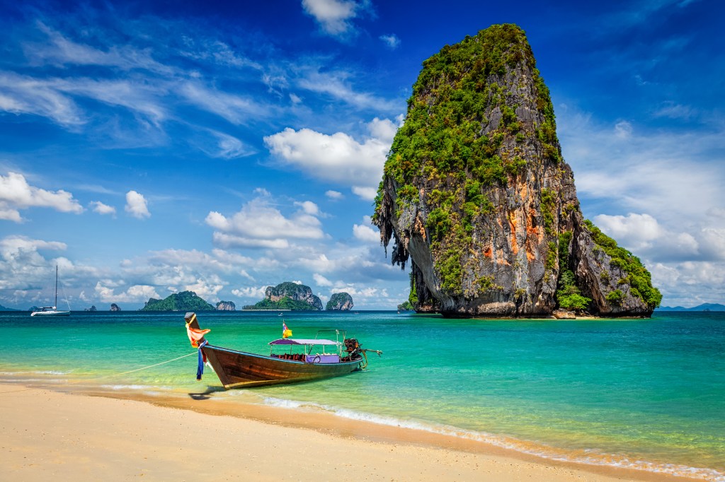 Boot am Strand mit riesigem Felsen im Hintergrund